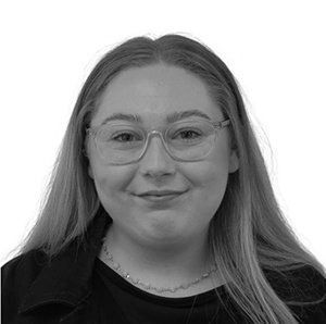 Portrait of a person with glasses smiling against a plain light background