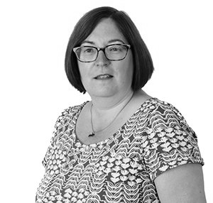 Portrait of a person wearing glasses and a patterned shirt against a plain white background