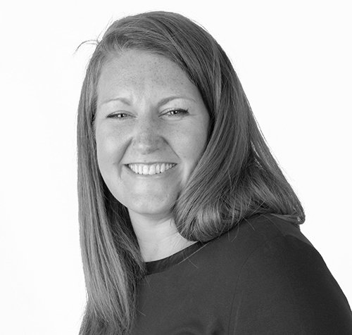 Smiling woman with long hair in a black top, facing the camera against a white background