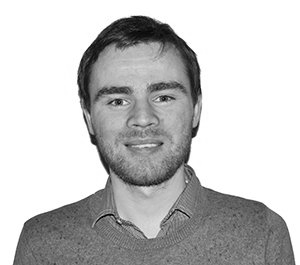 Black-and-white portrait of a smiling man in a sweater on a plain background