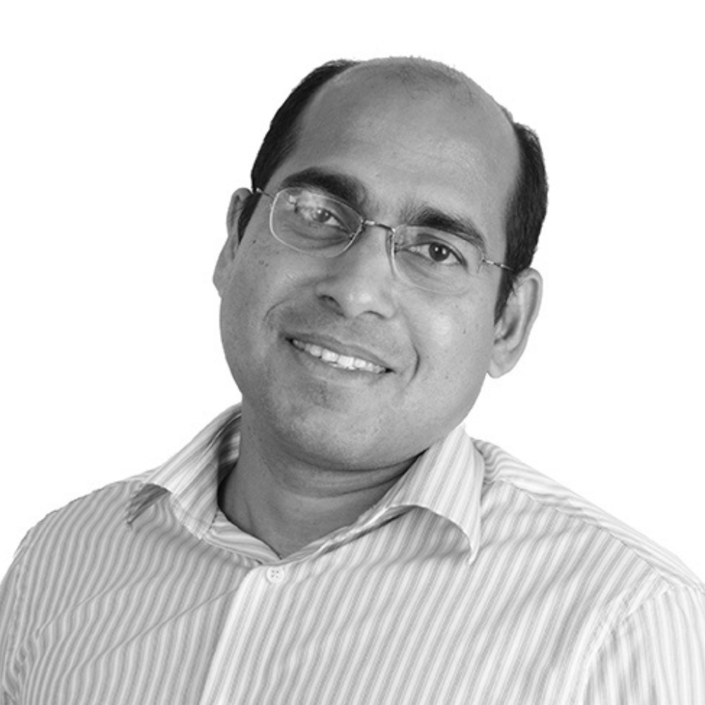 Smiling man in glasses wearing a striped shirt, photographed against a plain light background
