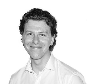 Black-and-white headshot of a smiling person in a white shirt