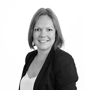 Smiling woman in a black blazer and white top on a plain white background