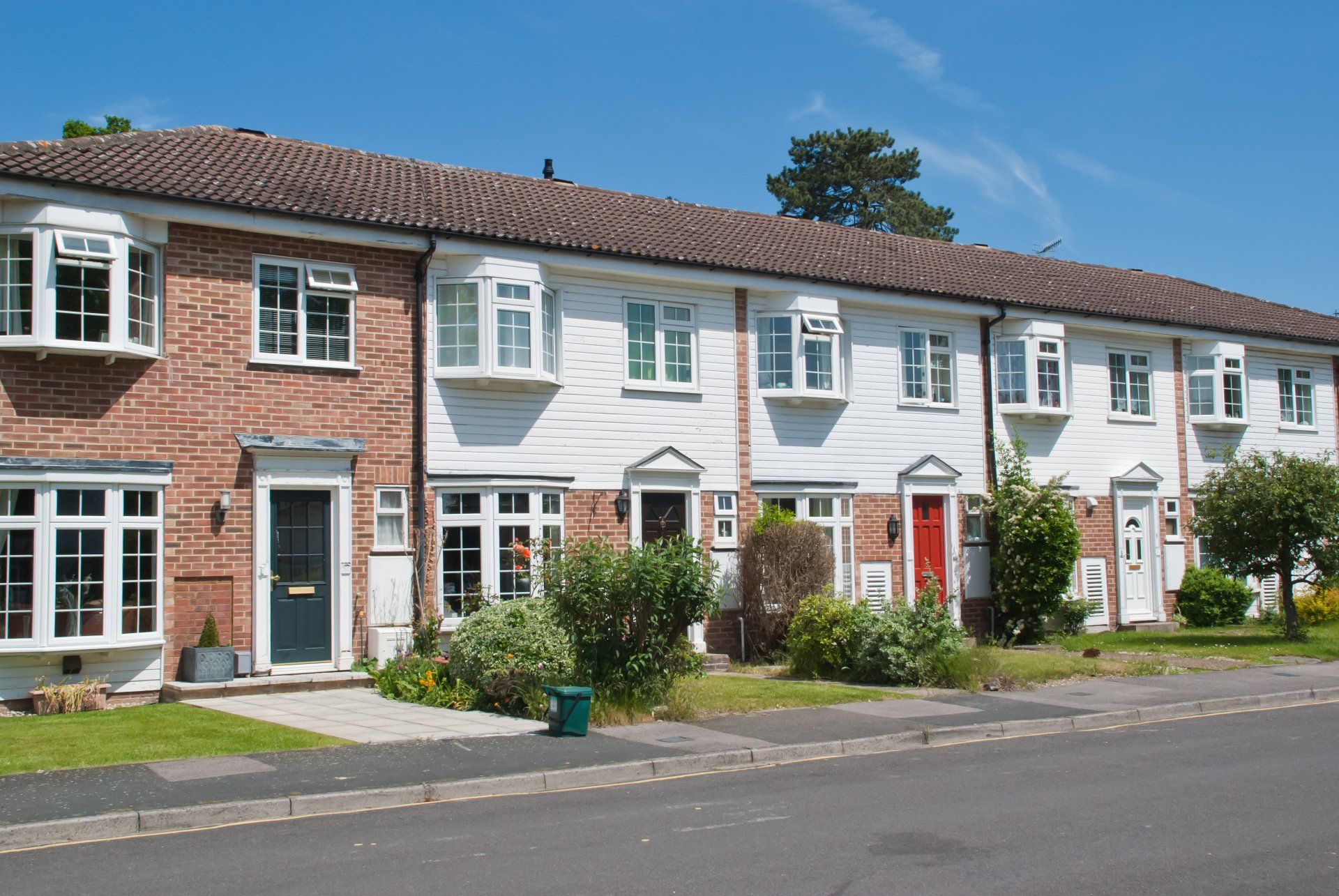 Row of colorful terraced houses with front gardens on a sunny street