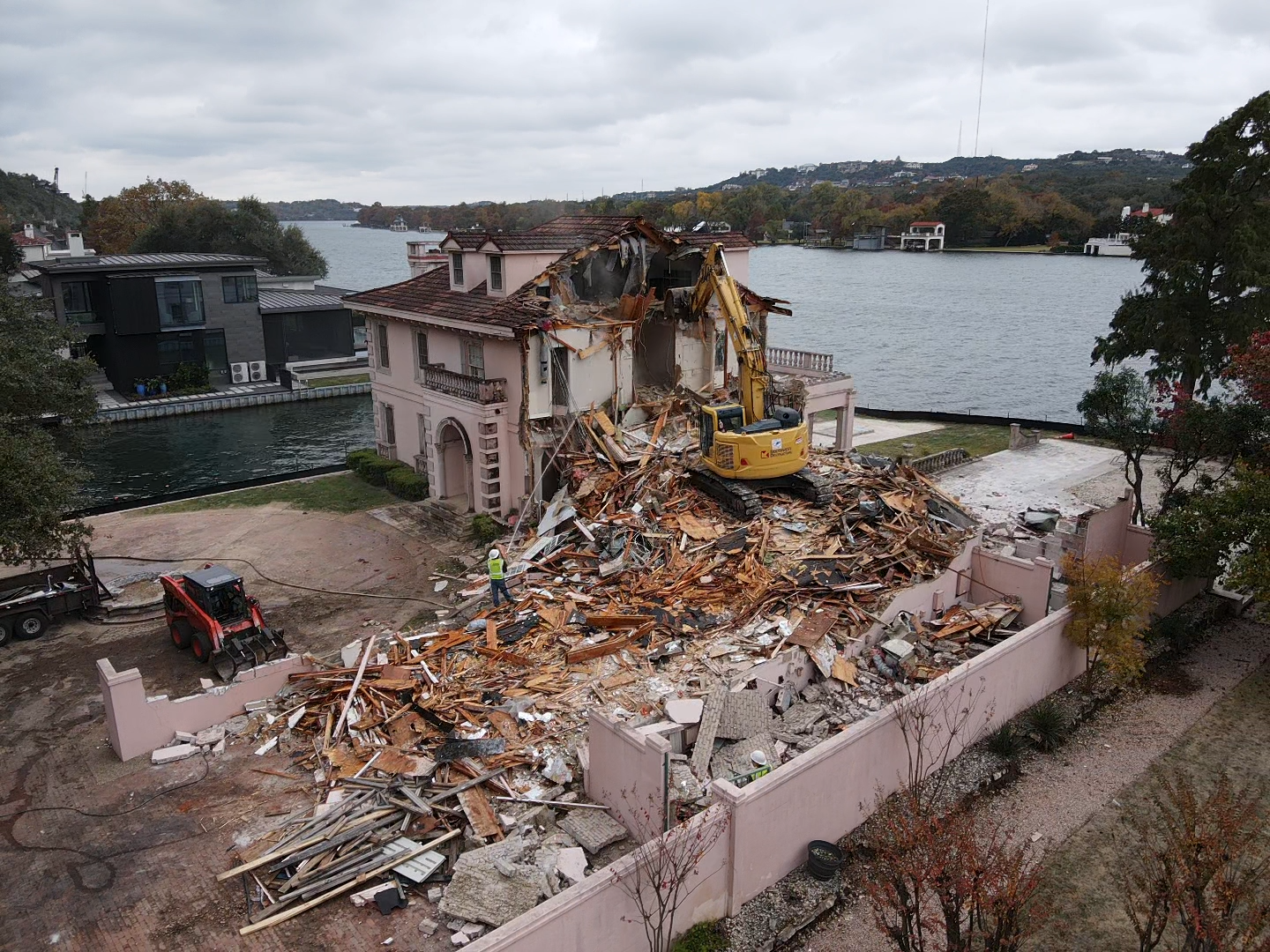 A large house is being demolished by a large excavator.