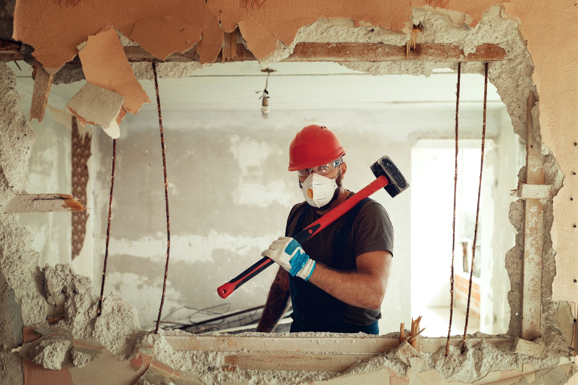 A man is breaking a wall with a hammer.