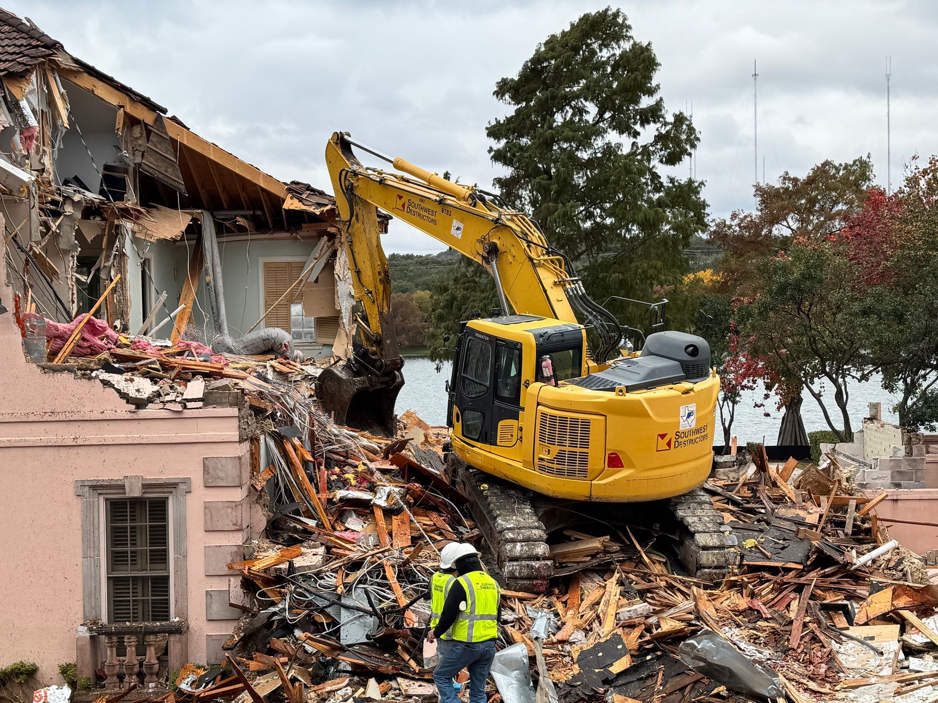 A large yellow excavator is demolishing a house.
