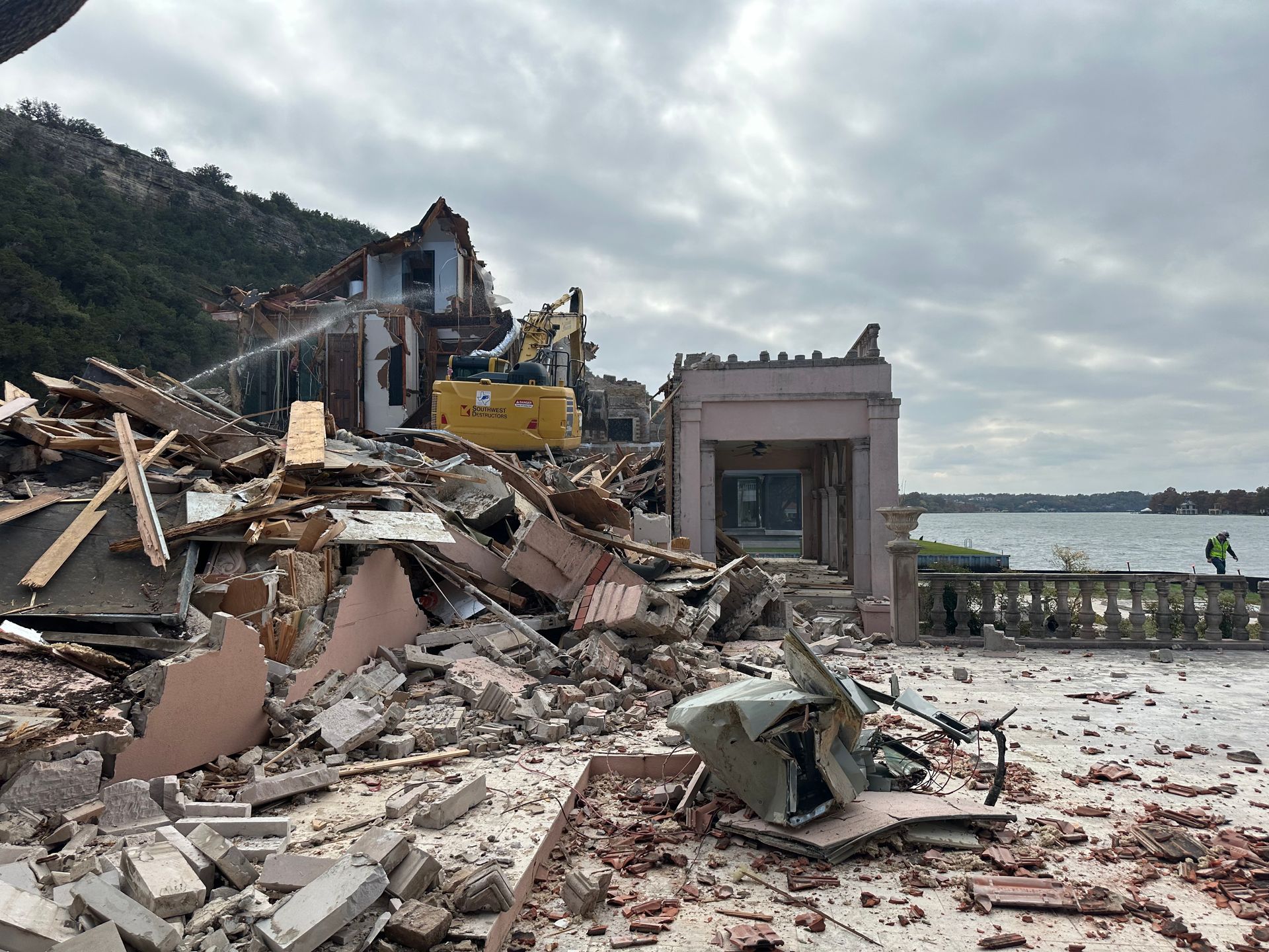 A large pile of rubble is sitting in front of a building that is being demolished.