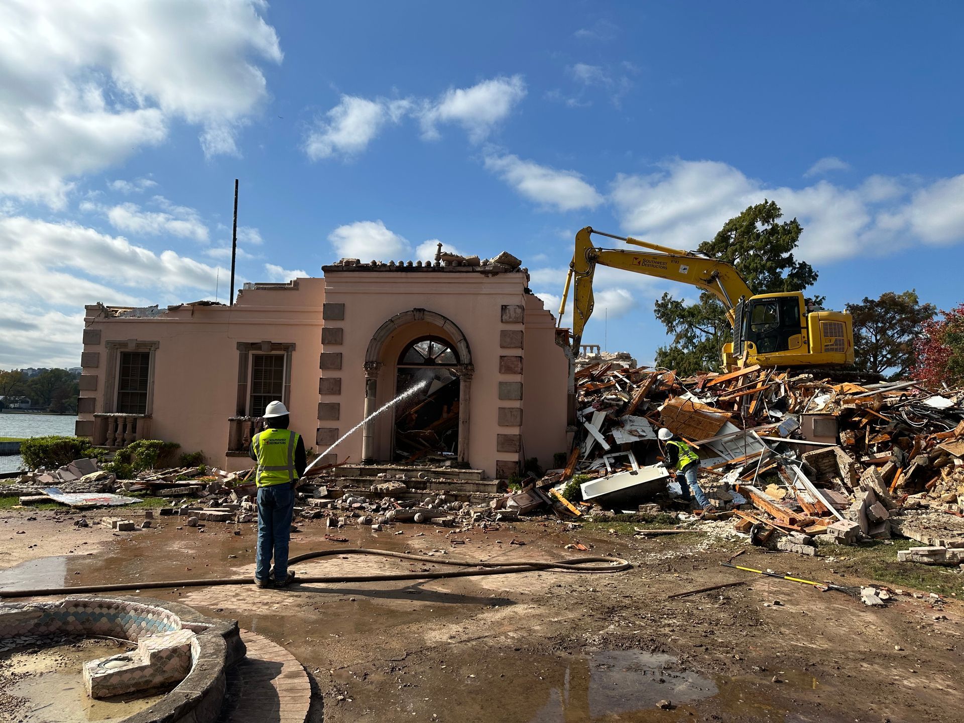 A man in a yellow vest is standing in front of a demolition site.