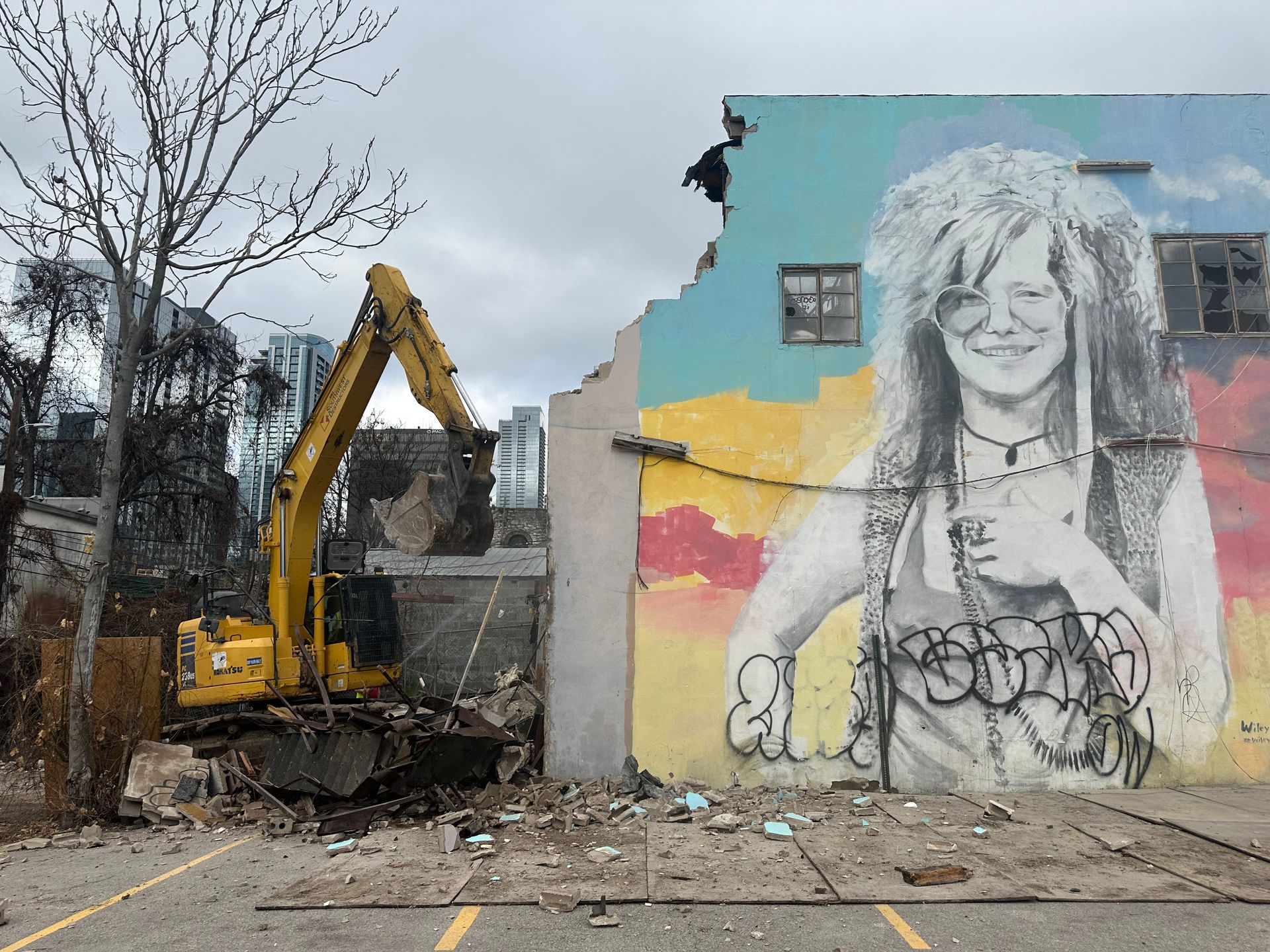 A large mural of janis joplin is being demolished by a bulldozer.