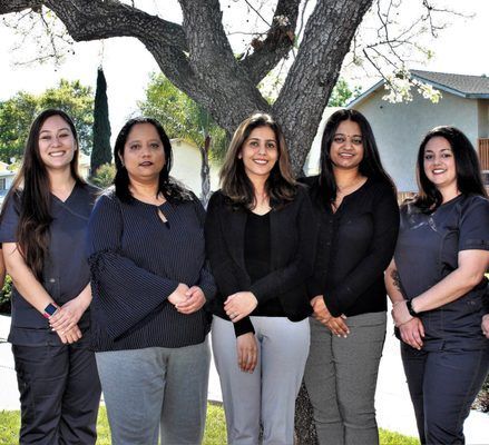 A group of women are posing for a picture in front of a tree