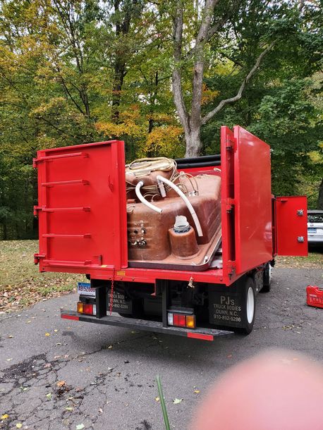 A red dump truck with a bathtub in the back is parked on the side of the road.