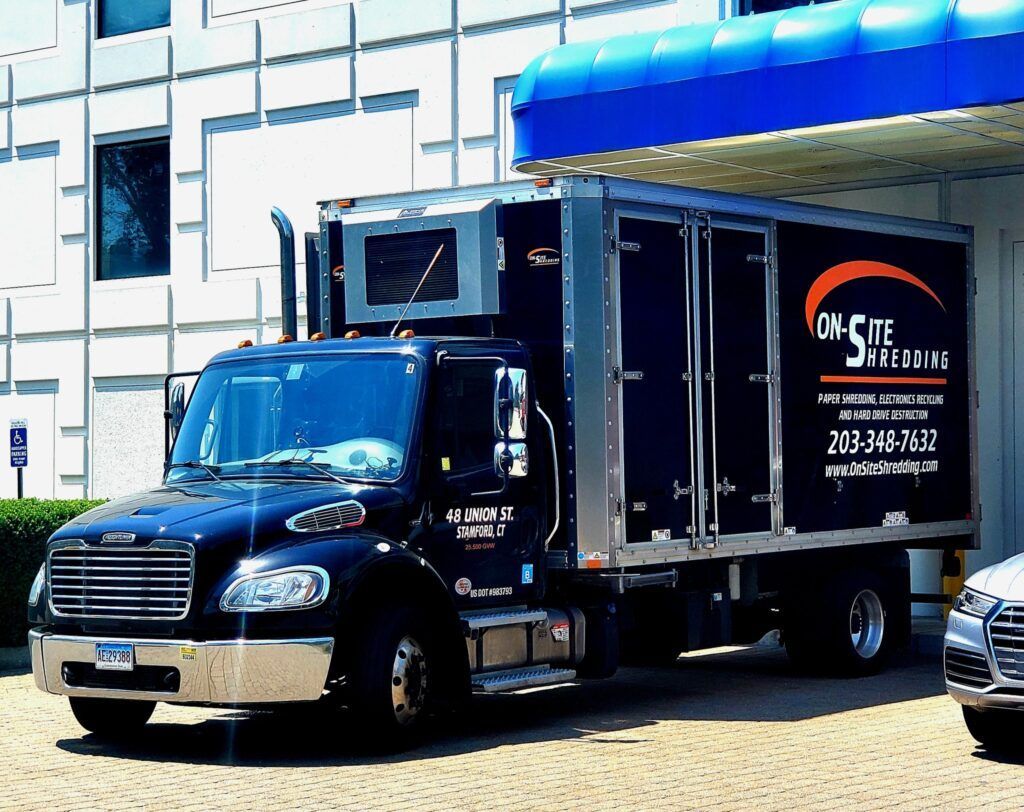 A black truck that says onsite recycling is parked in front of a building