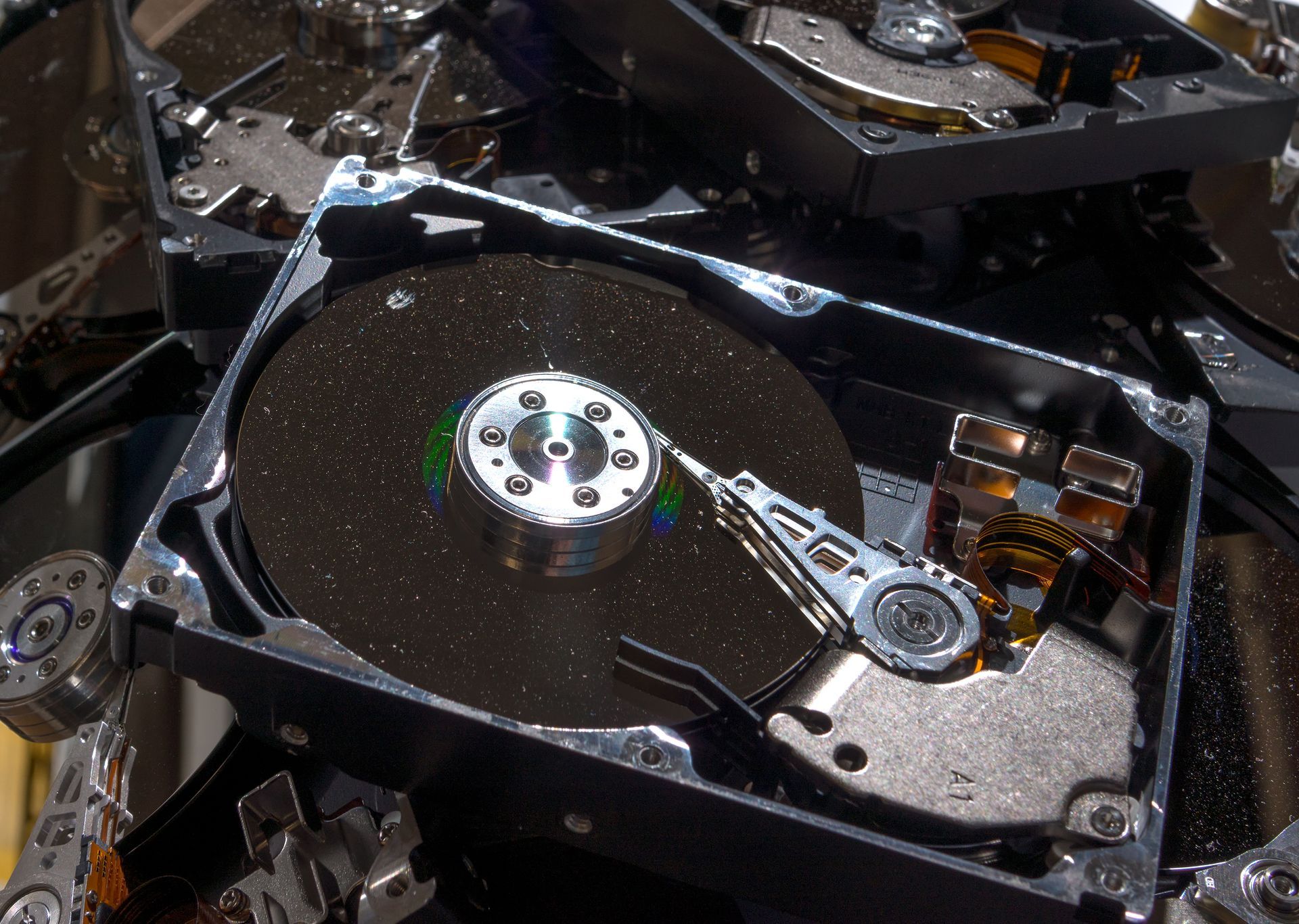 A broken hard drive is sitting on top of a pile of other hard drives