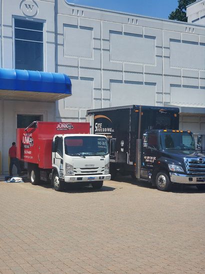 Three trucks are parked in front of a building with a blue awning