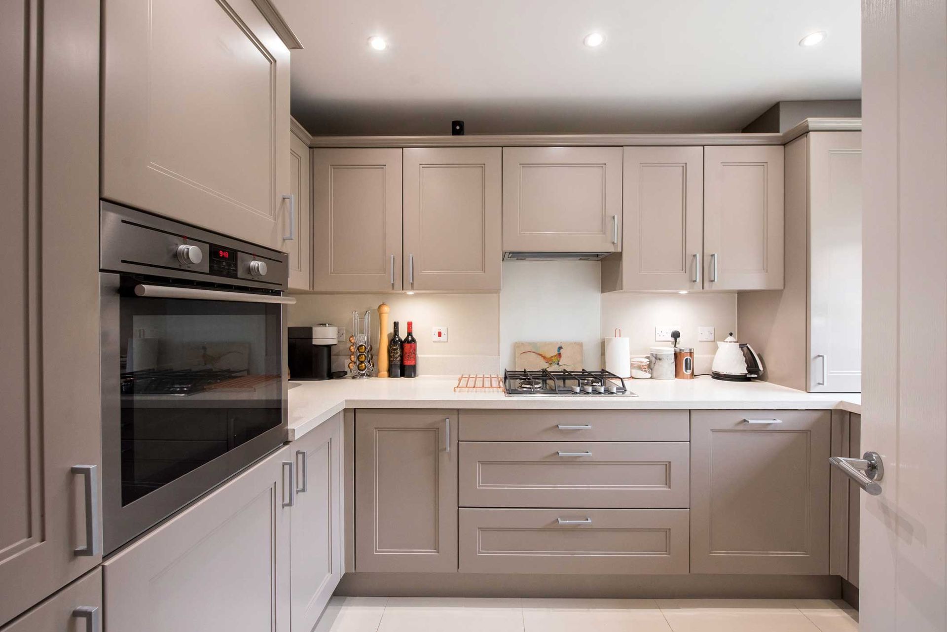 A general interior view of a small truffle-taupe-colored shaker-style fitted kitchen within a home A general interior view of a small truffle-taupe-colored shaker-style fitted kitchen within a home