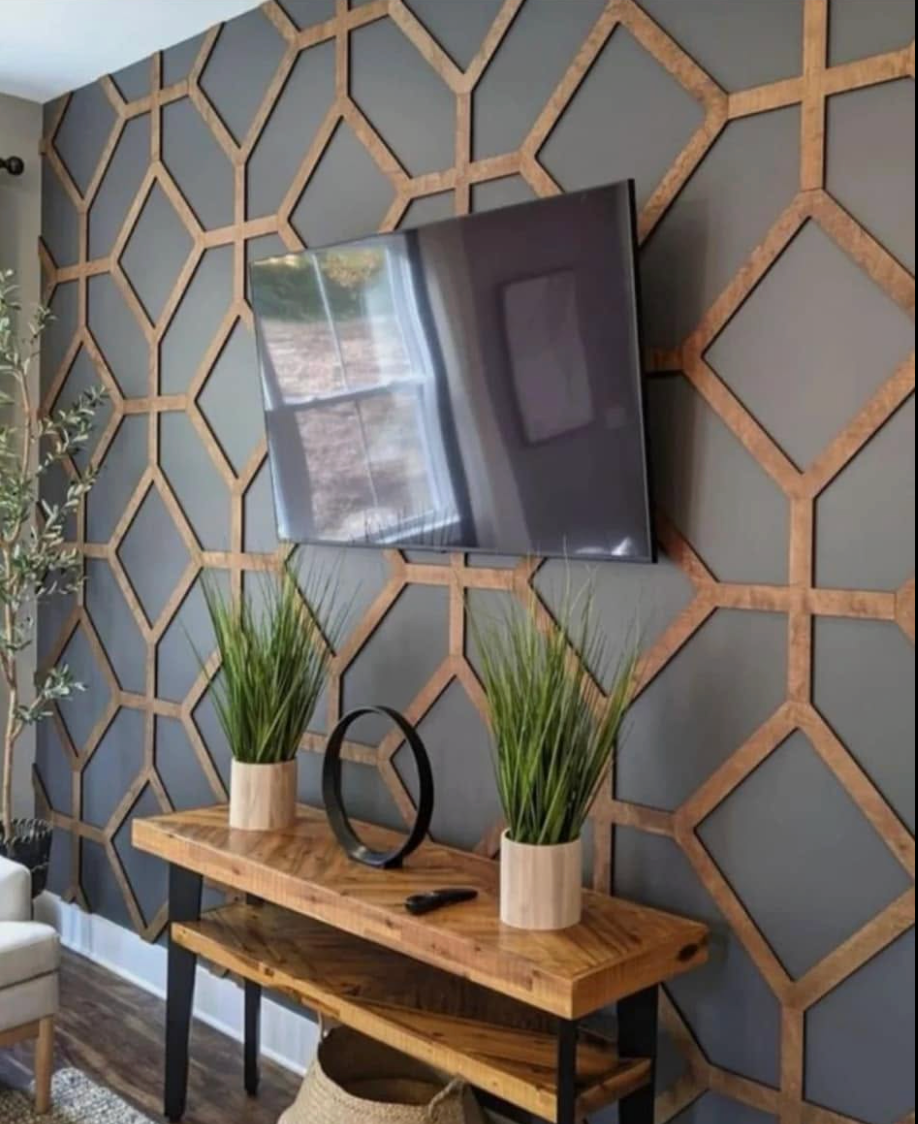 Wall-mounted TV above a wooden console with potted plants against a gray geometric accent wall