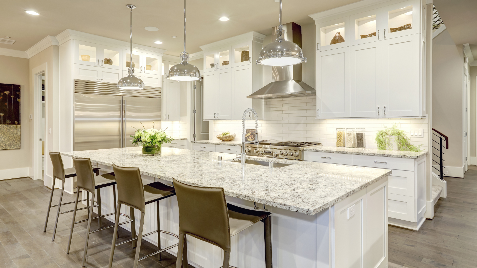 Bright modern kitchen with white cabinets, large island, pendant lights, and bar stools