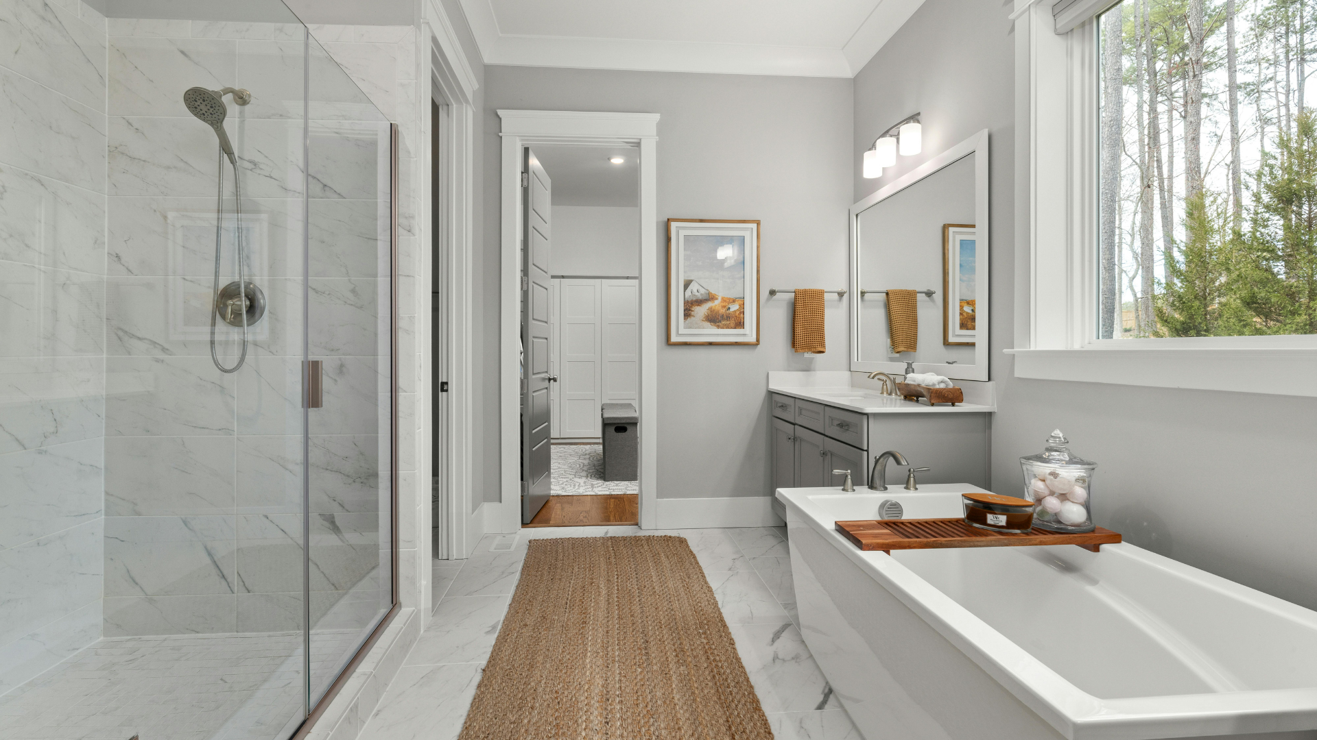 Bright modern bathroom with glass shower, freestanding tub, double vanity, and window light