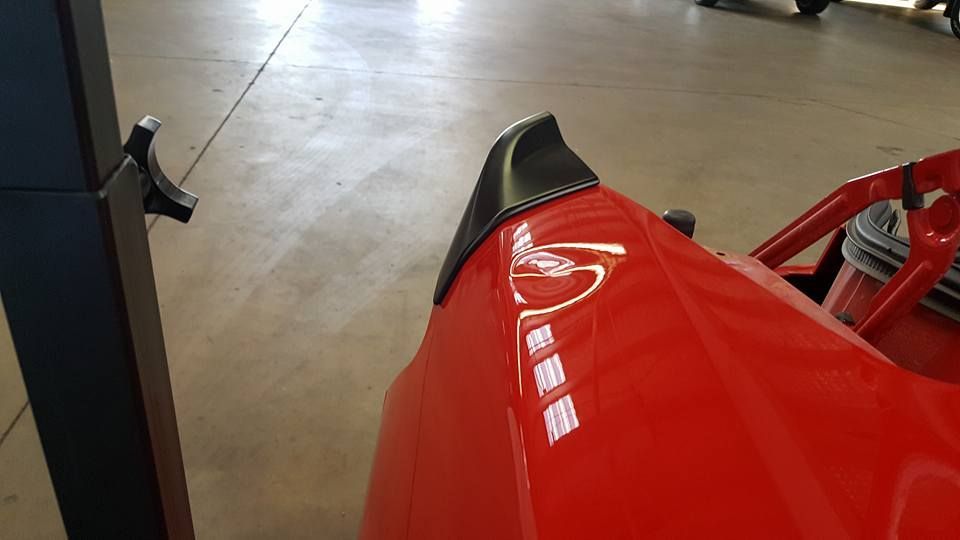 Close-up of a maroon car’s dented front fender above the wheel.