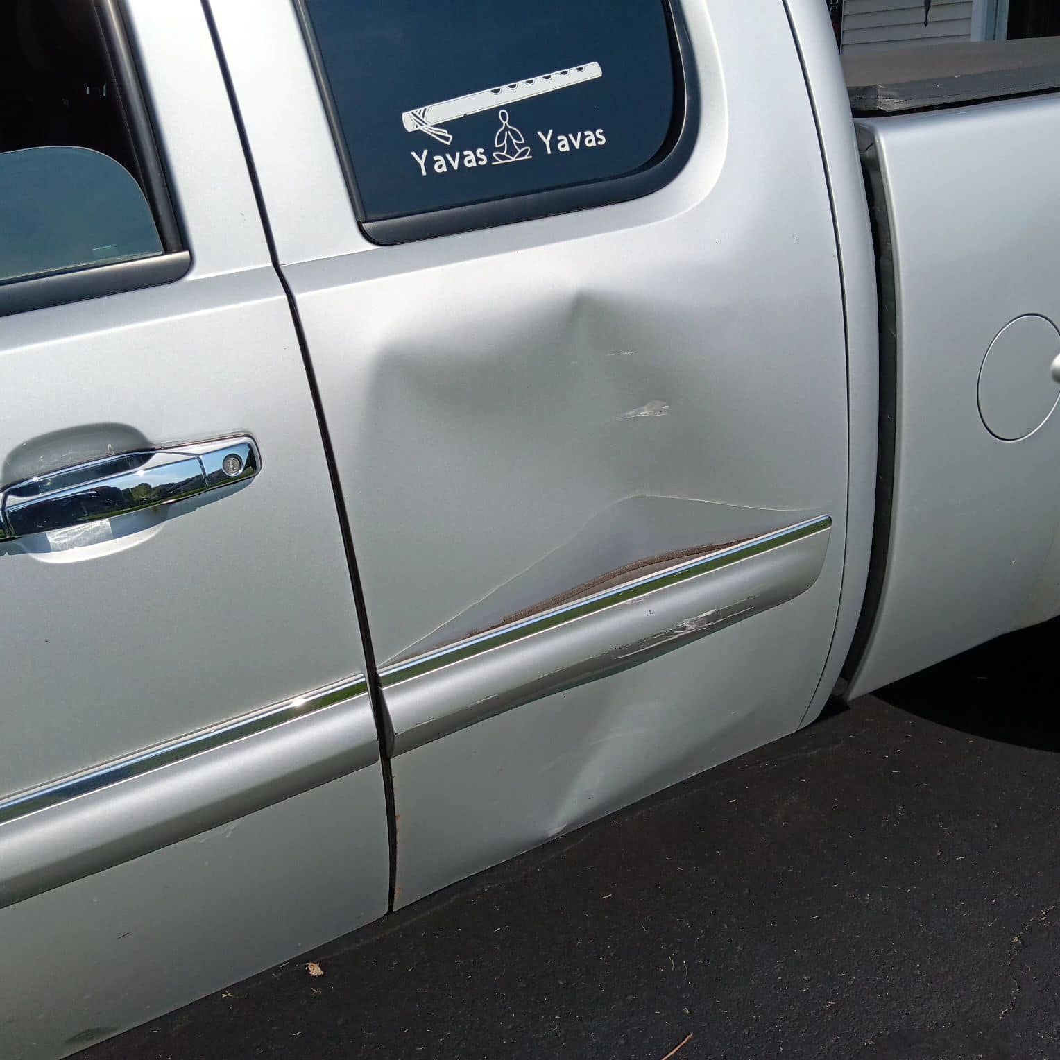 Silver pickup truck side panel with a dent and scratch near the rear door.