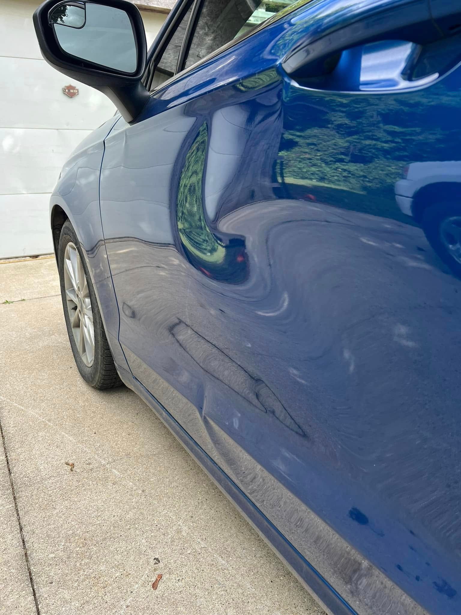 Silver pickup truck side panel with a dent and scratch near the rear door.