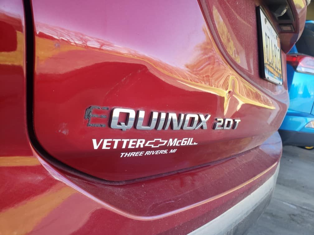 Close-up of red car rear badge reading “QUINDX 20T” and “VETER-C-ME BL,” with chrome trim.