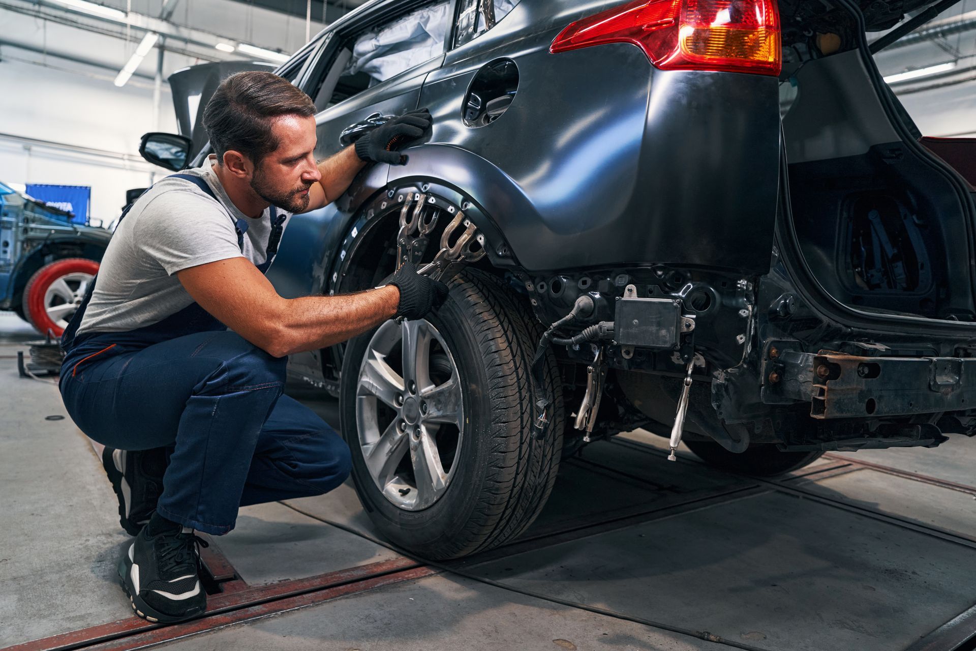 Mechanic inspecting a black car’s rear wheel in an auto repair shop