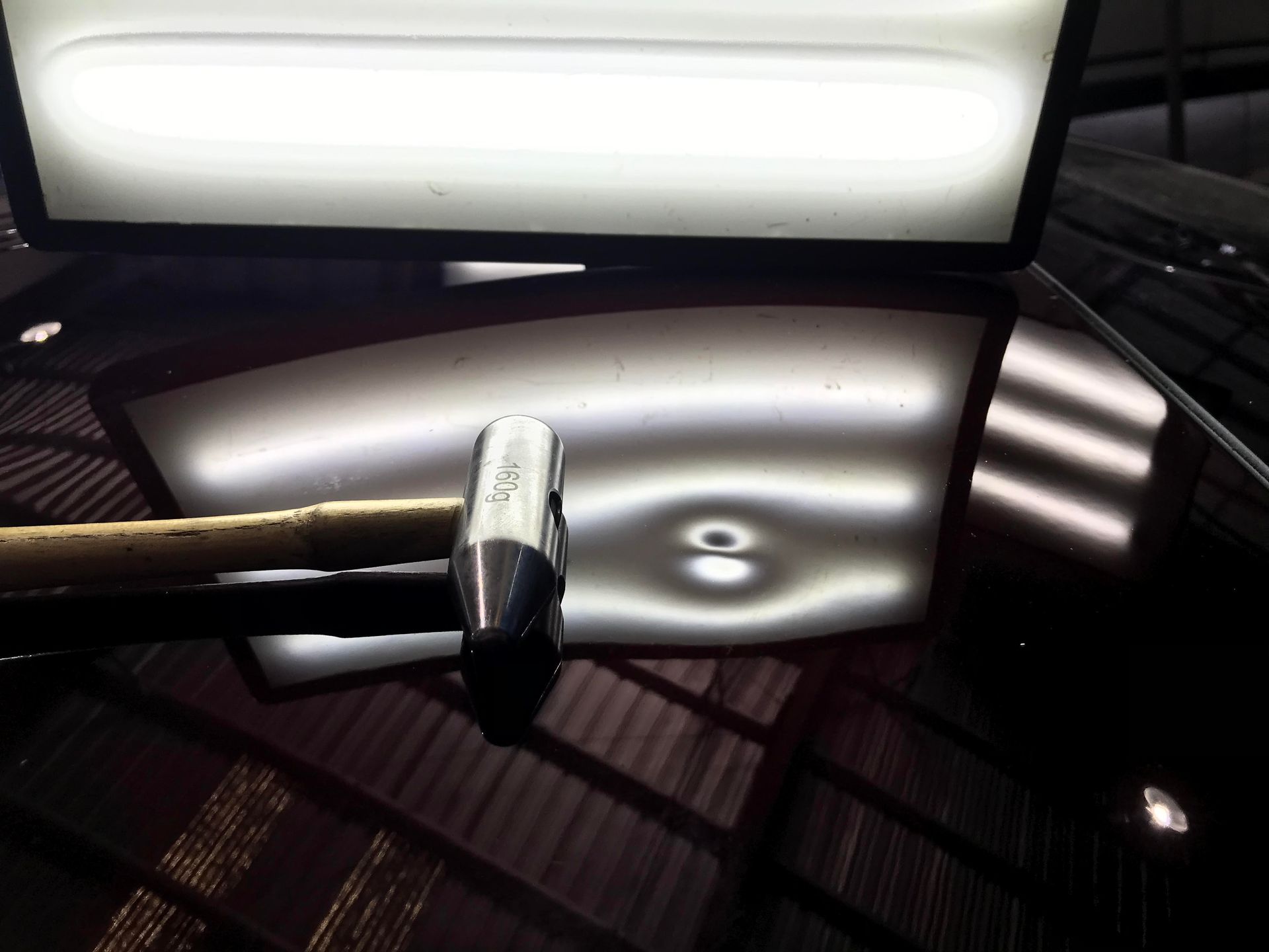 Overhead lights reflected in a dark glossy ceiling with a metal rod in the foreground