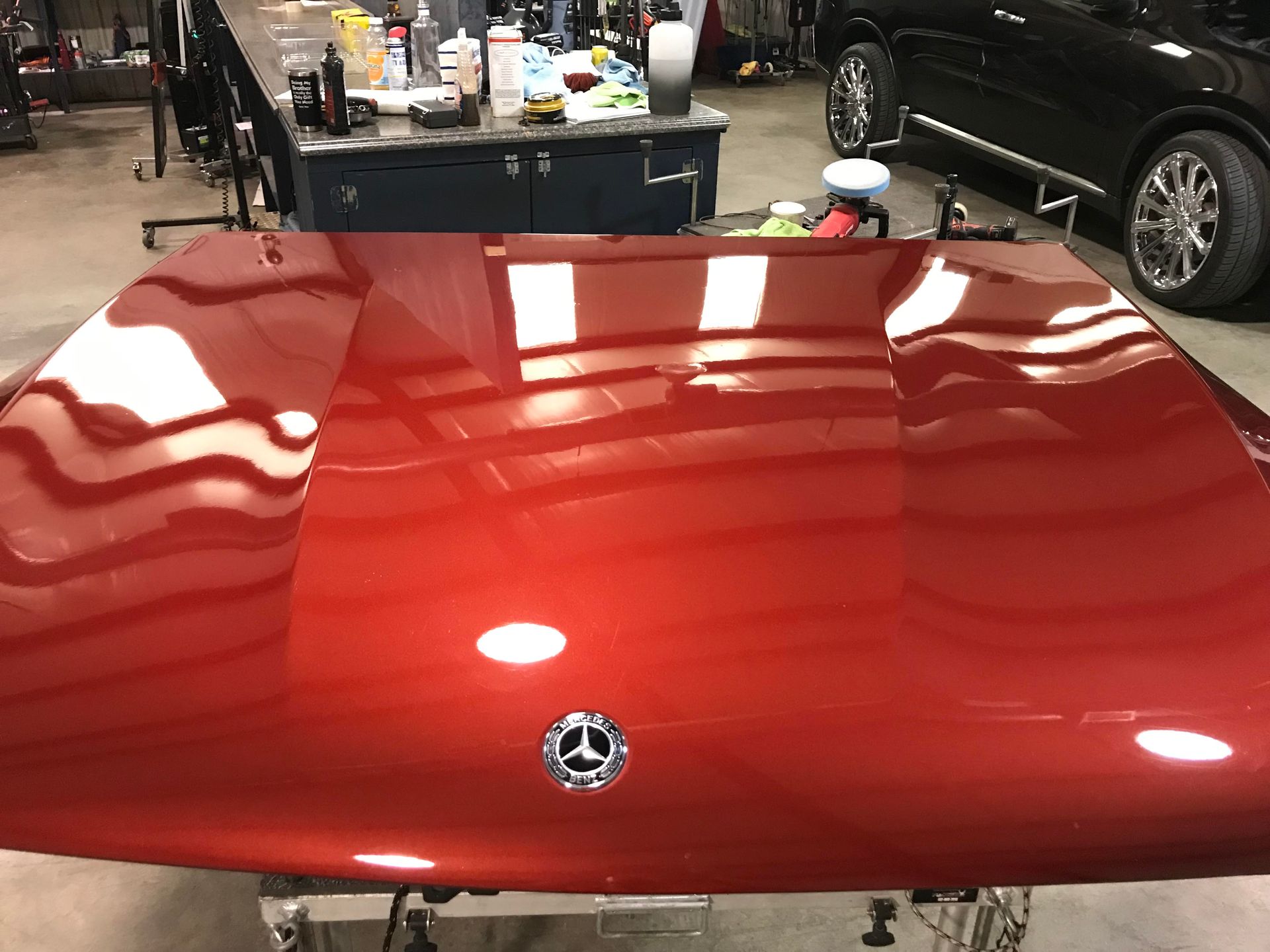 Red car hood with glossy reflections in a garage or workshop setting
