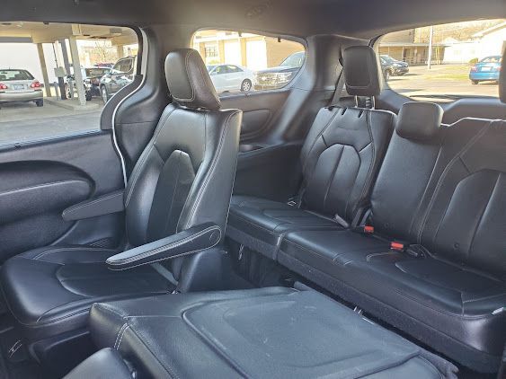 Black leather car interior with two front bucket seats and a rear bench seat, viewed from the back.