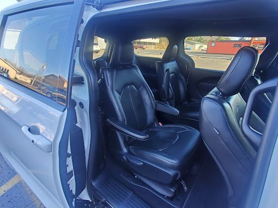 Open van with sliding door open, showing black leather seats inside.
