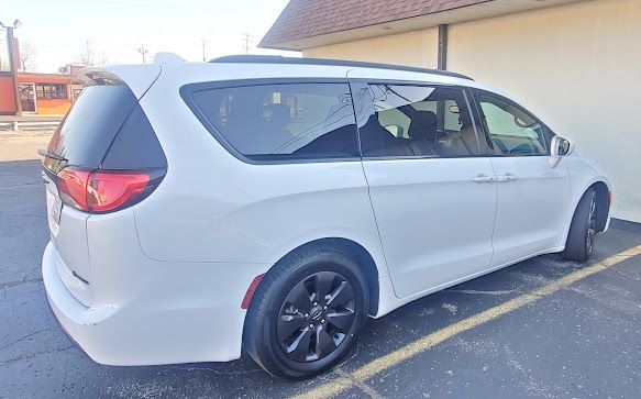 White minivan parked in a lot beside a building, viewed from the rear side.