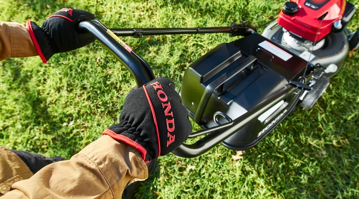 Hands on a Black Honda Mower — Great Lakes Mowers & Chainsaws In Tuncurry, NSW