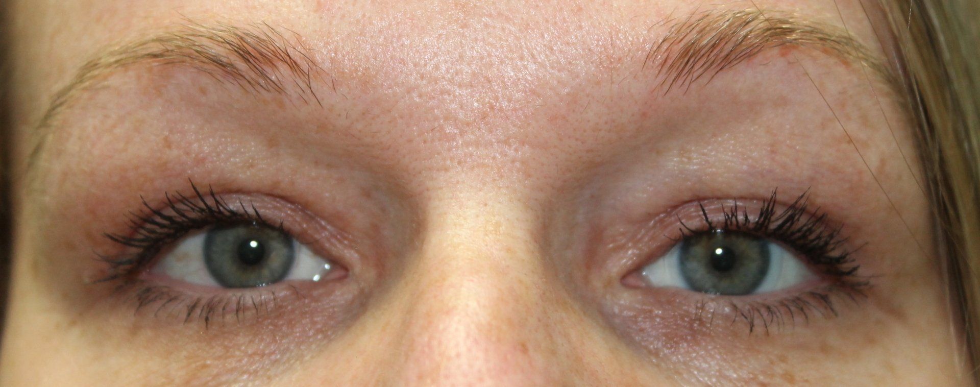 Close-up of a person’s eyes with light blue-green irises and mascara
