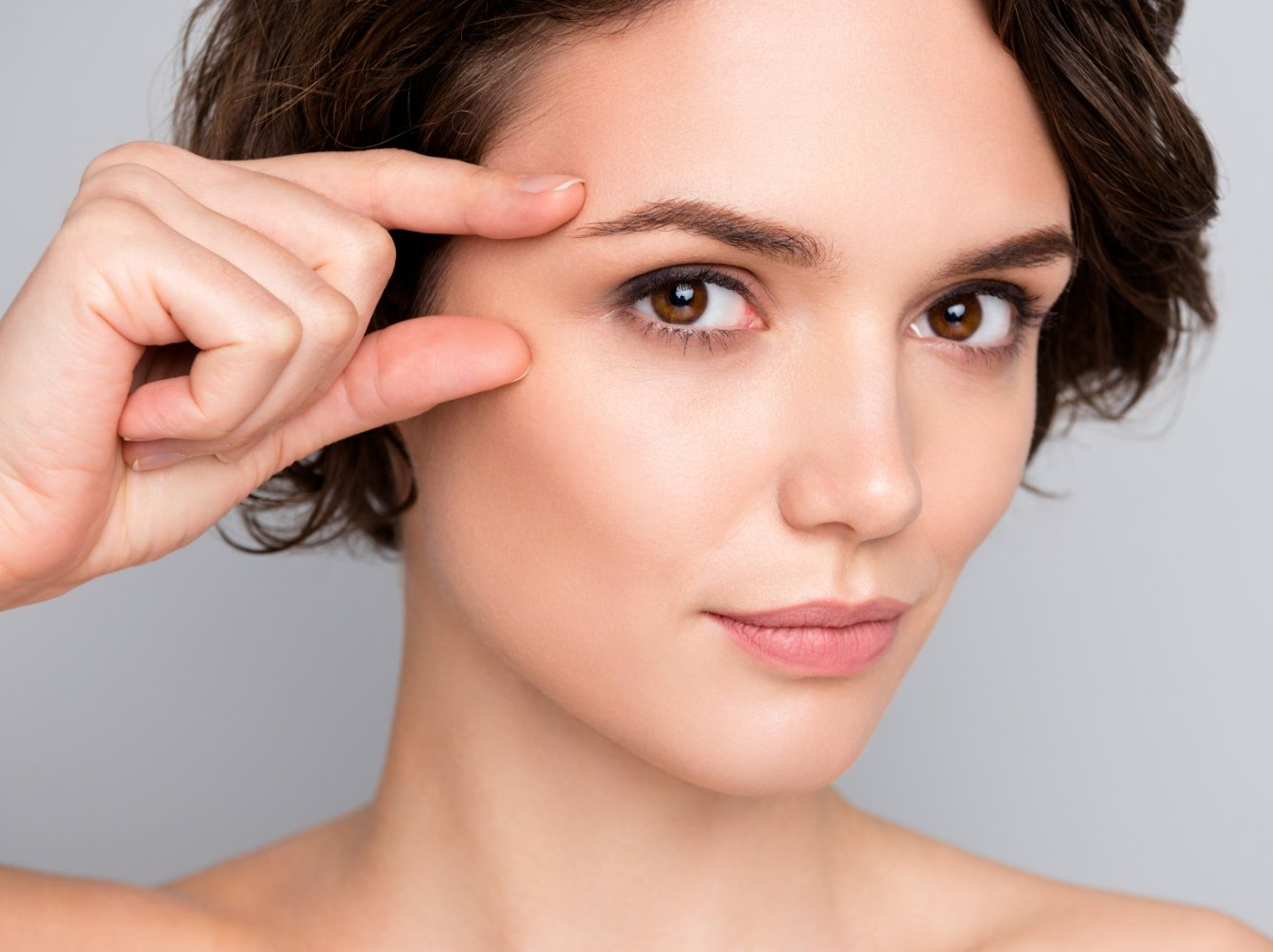 A woman is touching her eye with her finger.
