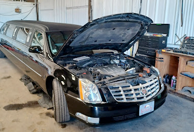 A black limousine with the hood up is sitting in a garage.