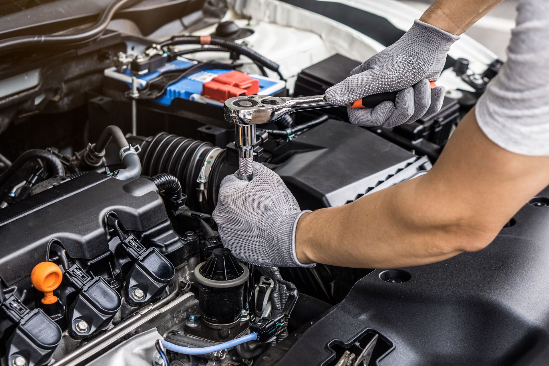A man is working on the engine of a car with a wrench.