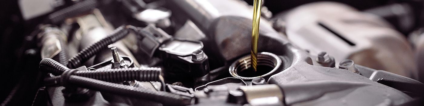 Oil pouring into an engine. Close up of engine components; the oil stream is visible against the metal.