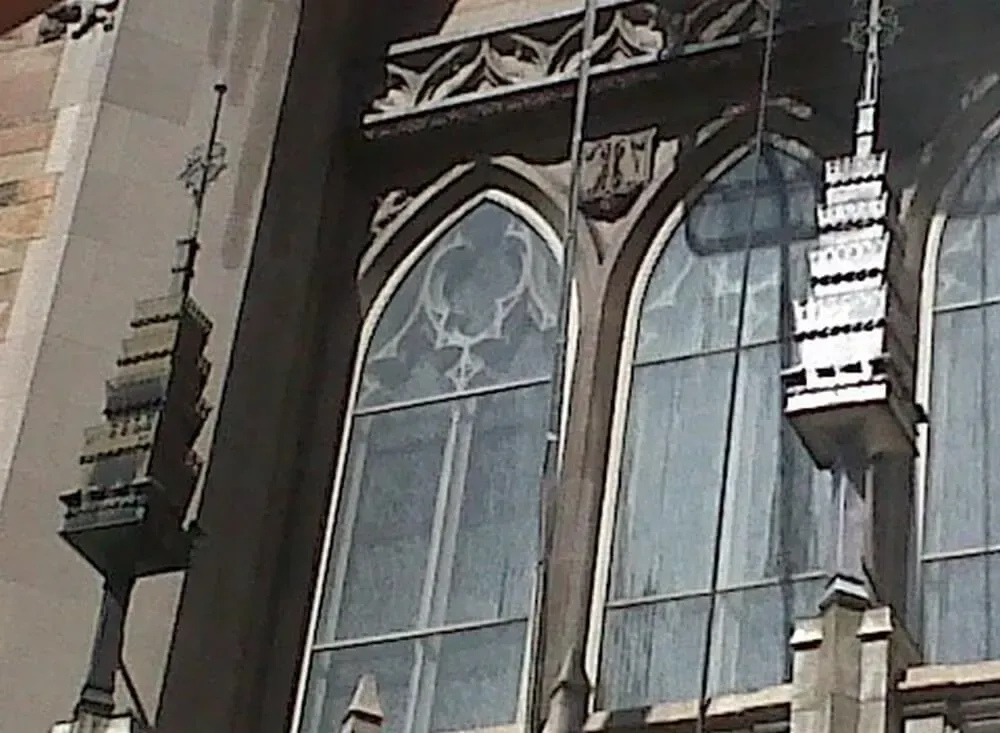 Gothic arched windows with decorative spires, set in a stone building.