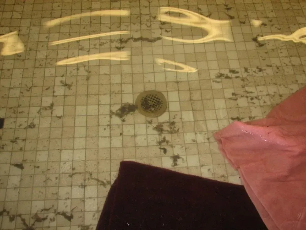 Water-filled tile pool with drain, and two fabrics in burgundy and pink resting on the edge.
