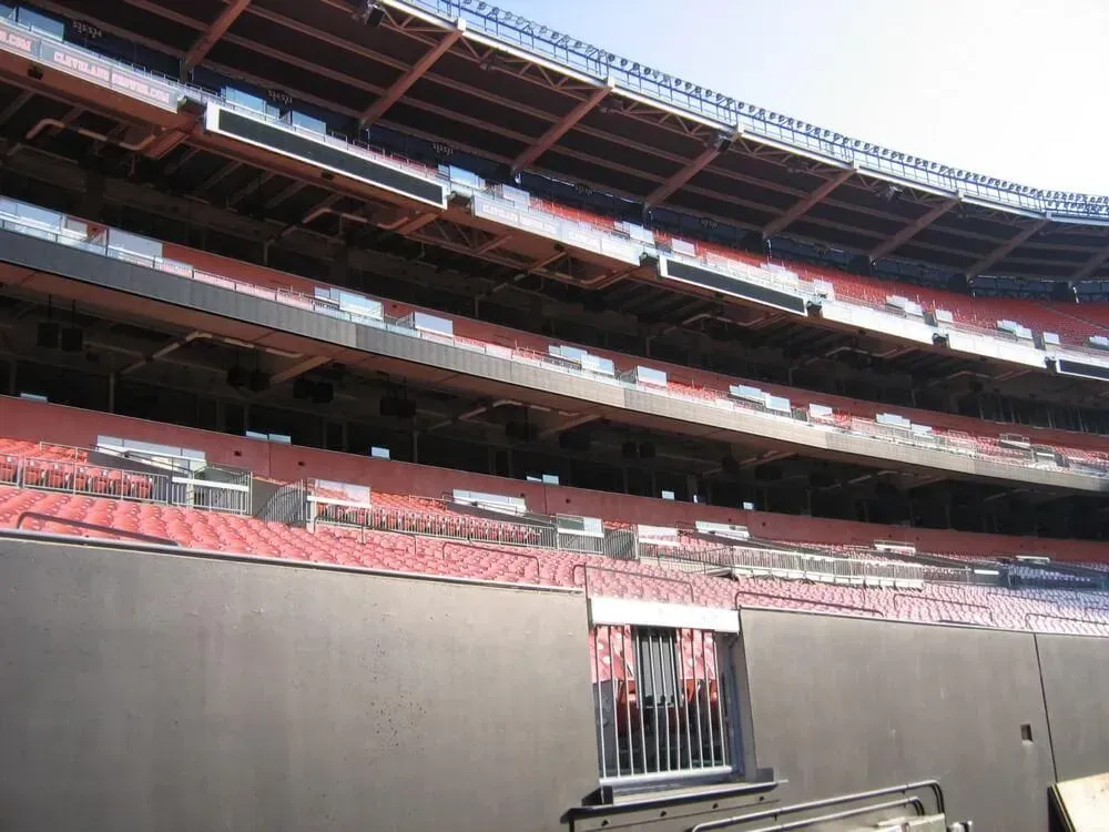 View of empty stadium seating, mostly red, with black walls and a gated entrance.