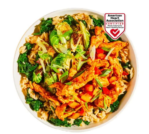 Colorful rice bowl with broccoli and chicken, topped with a small American Heart Association label