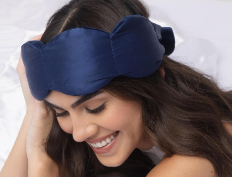 Smiling woman resting with a navy blue sleep mask on her forehead