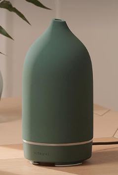 Matte green tabletop diffuser or humidifier with a wooden base on a desk