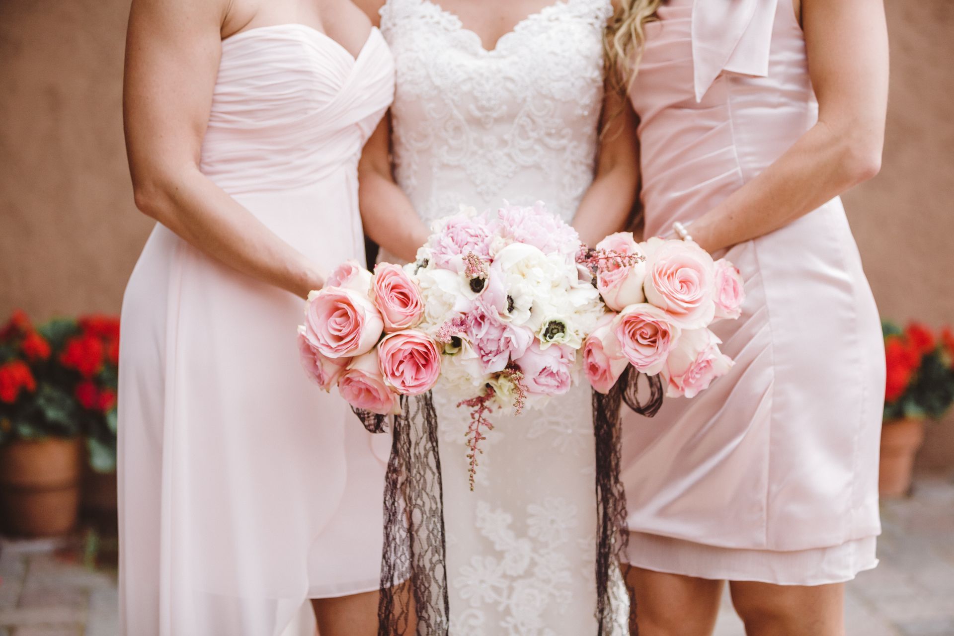 A bride and her two bridesmaids are posing for a picture with their bouquets of flowers.