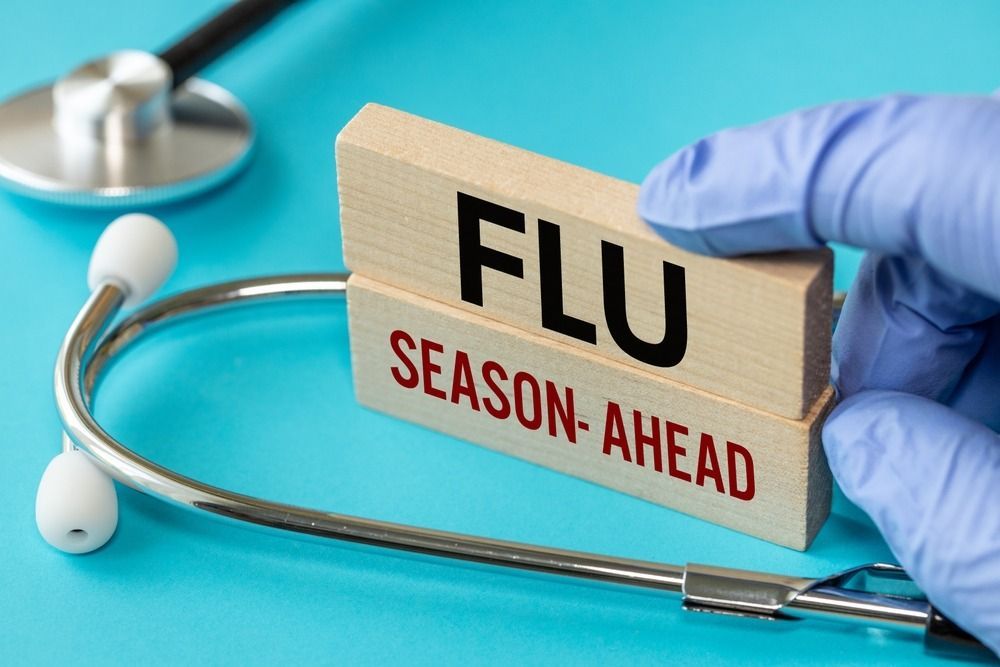 A doctor is holding a wooden block that says flu season ahead.