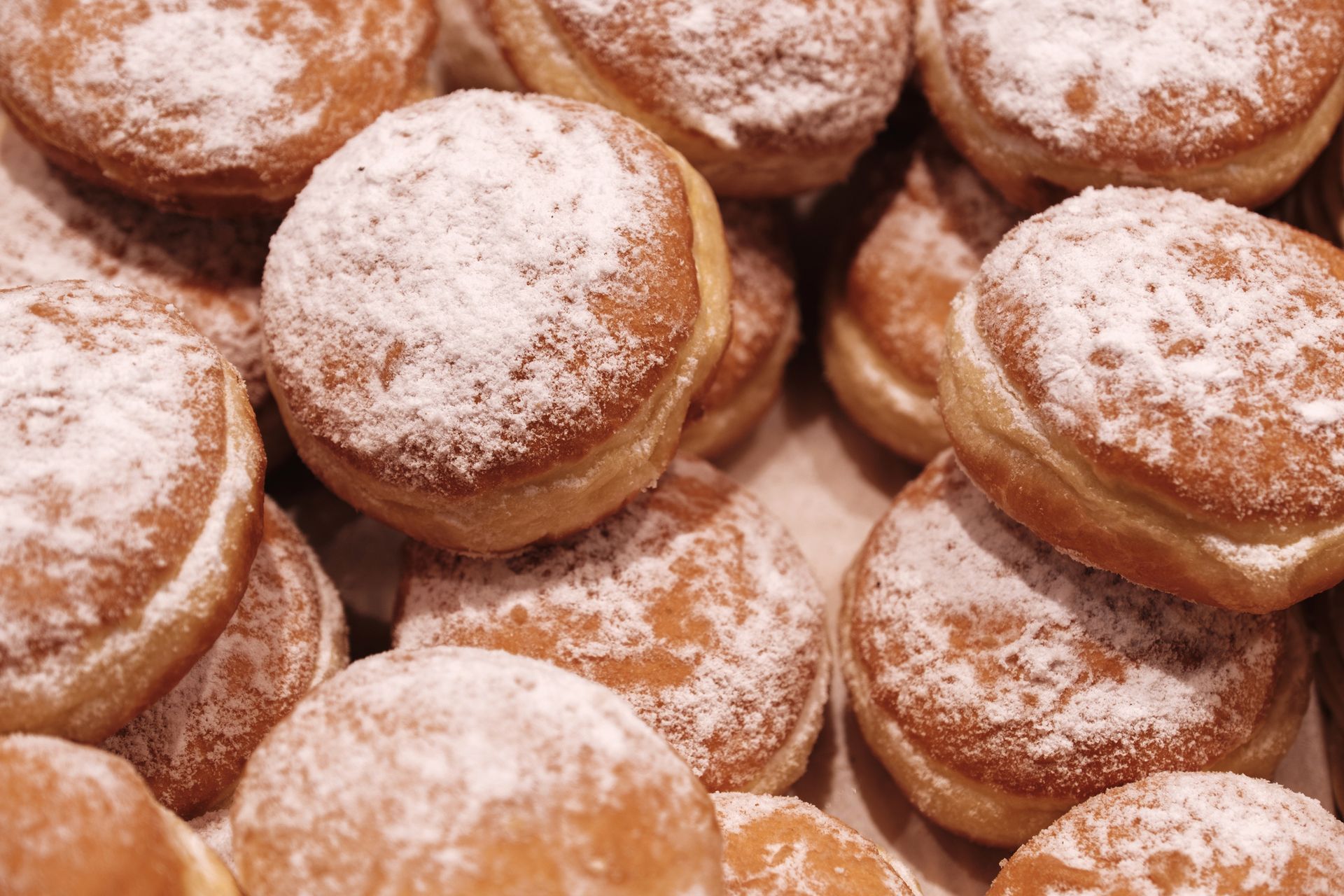 Primo piano di diverse ciambelle ricoperte di zucchero a velo.