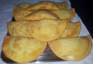 Un piatto di pasticcini fritti dorati. Alcuni sono impilati l'uno sull'altro.