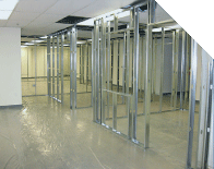 Empty office space with exposed metal framing and fluorescent lights, unfinished walls and shiny floor
